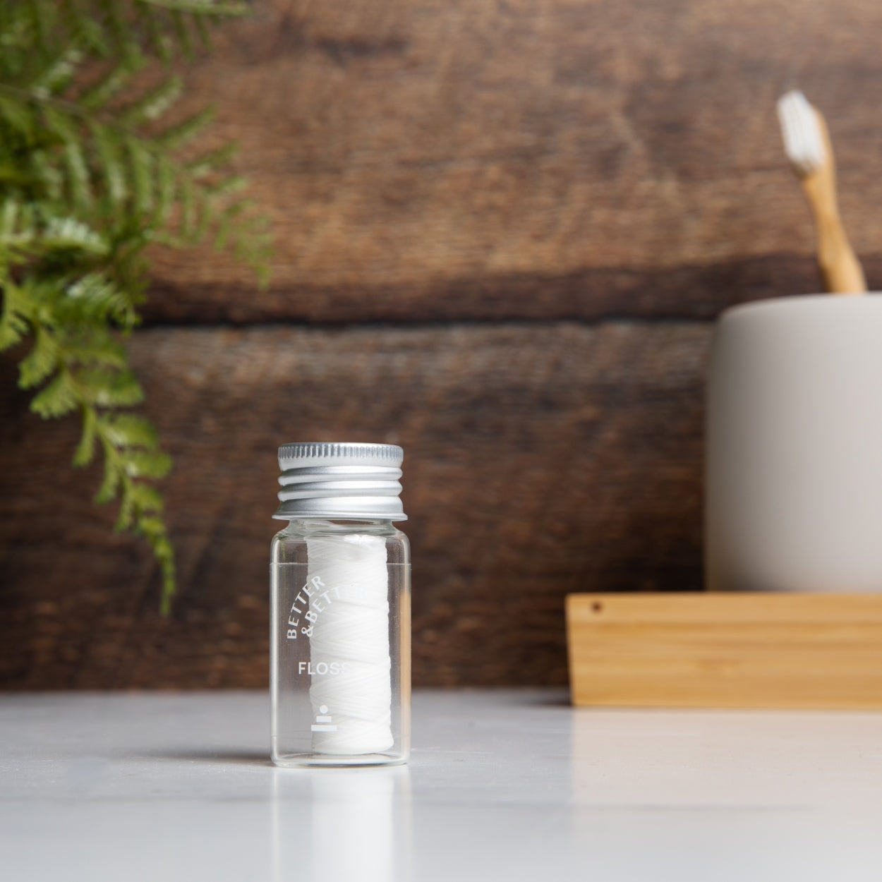 Natural floss in a refillable glass jar on a bathroom counter